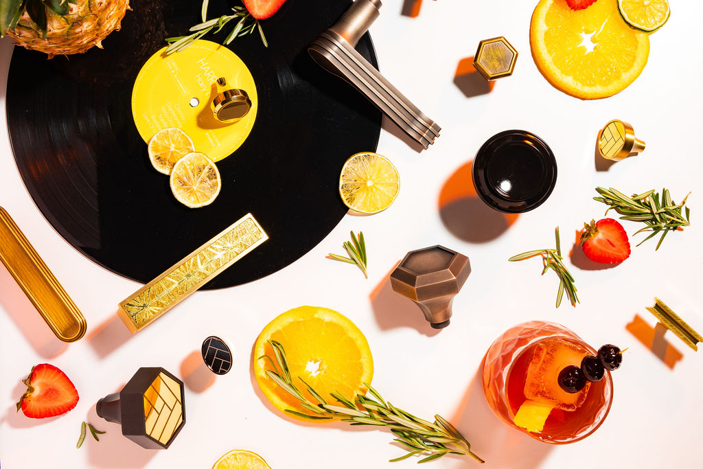 Flat-lay of cocktail tools, citrus garnishes, and a craft cocktail on a vinyl record